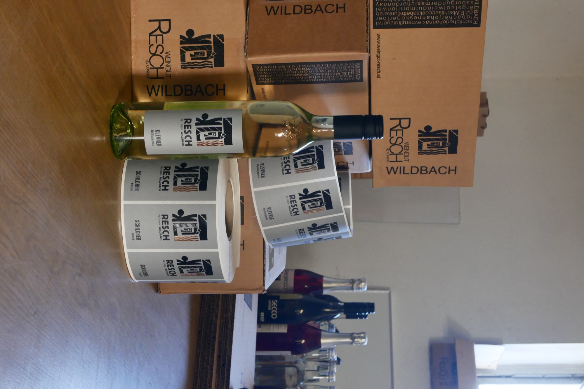 Eine Flasche Weißwein vom Weingut Resch zwischen Kartons und Etikettenrollen